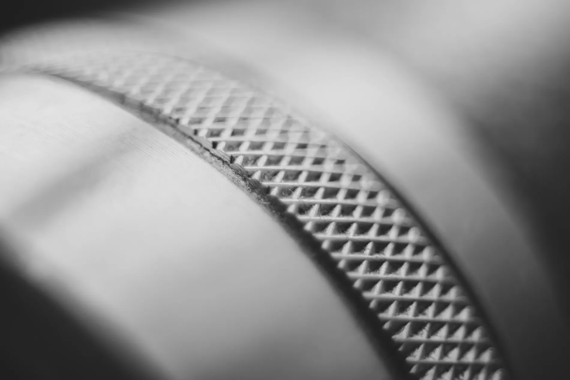 Diamond knurling machined into a steel cylinder, the pattern sharpening from blur into focus across the frame.