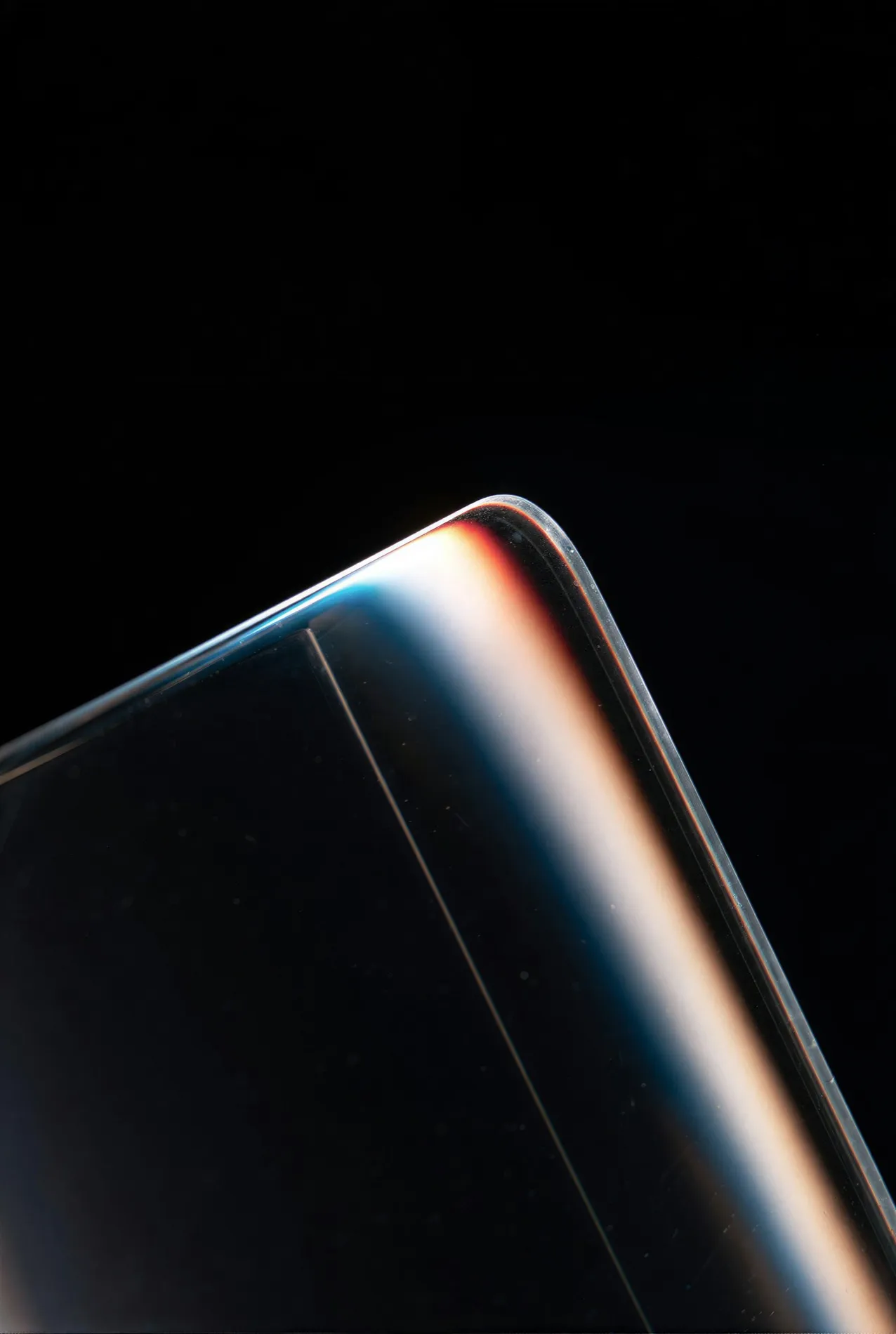 The rounded edge of a sheet of glass, carrying a single unbroken line of light.