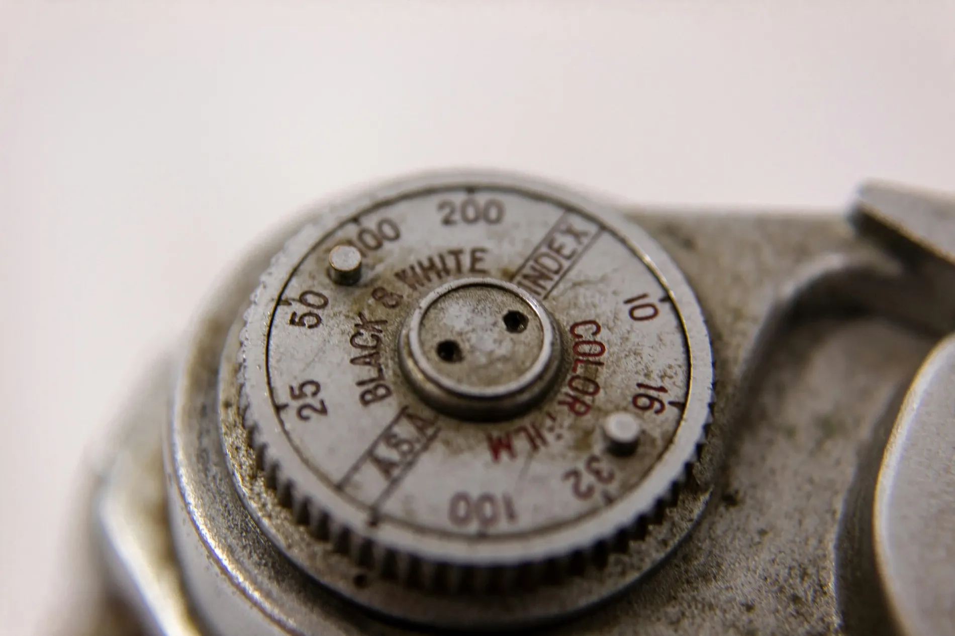 The calibrated dial of a hand-held meter, its numerals worn back to the brass.