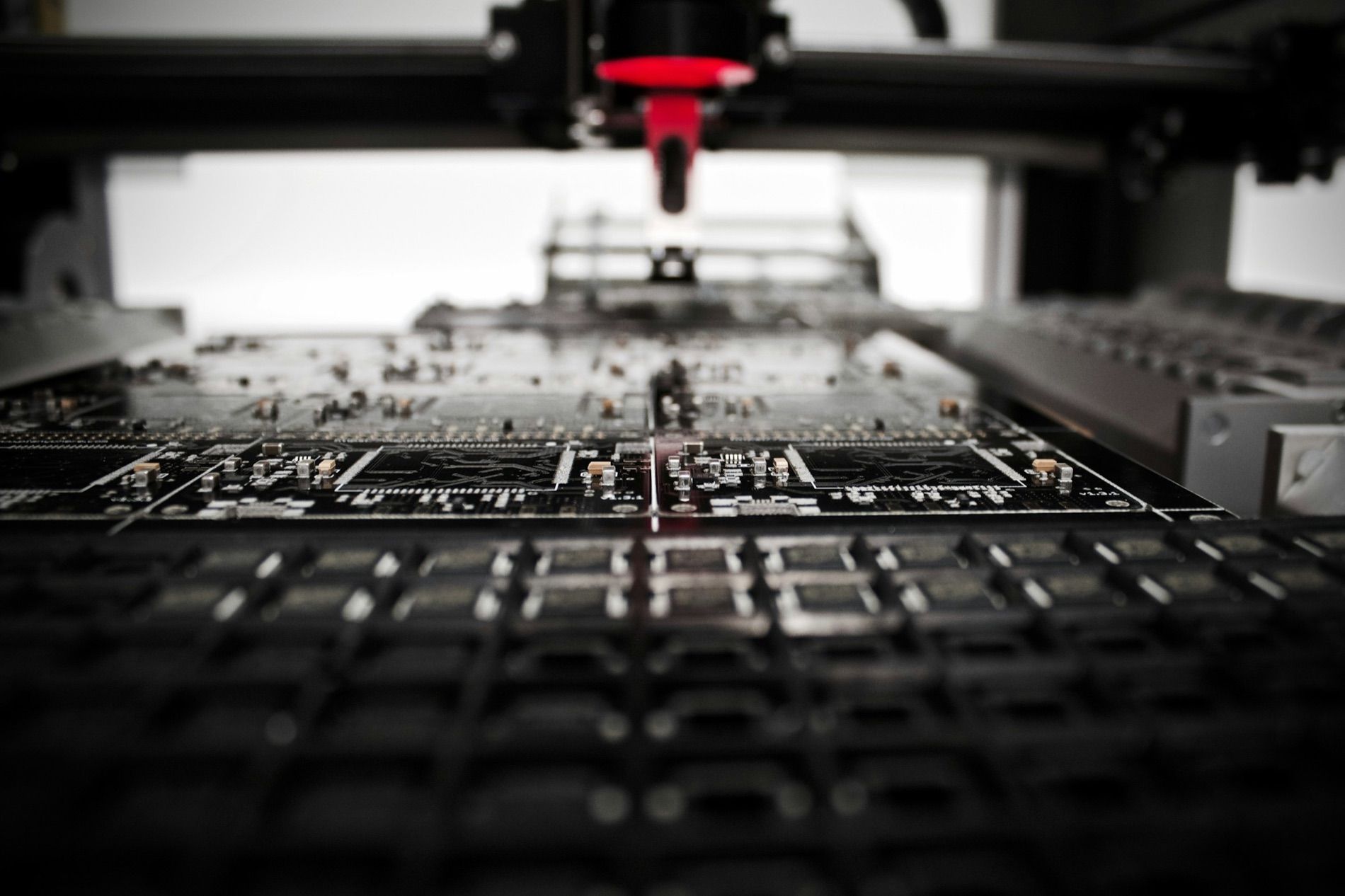 A pick-and-place head lowered over a dark circuit board