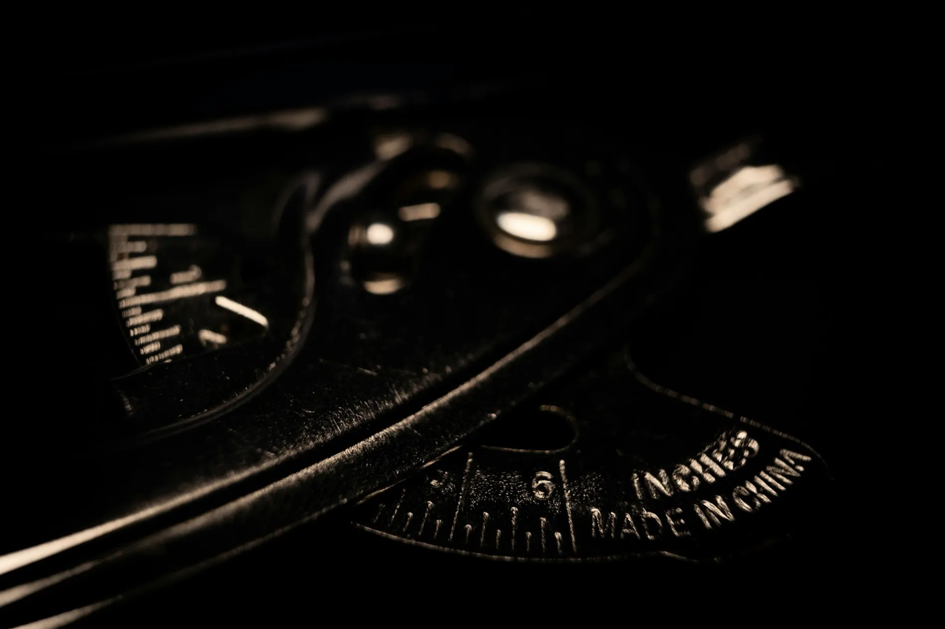 A gauge photographed in near-darkness, the words stamped into its face just legible at the bottom edge.